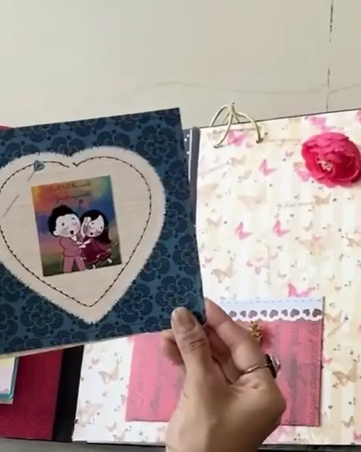 A hand turning the heart-shaped page of a handmade photo album